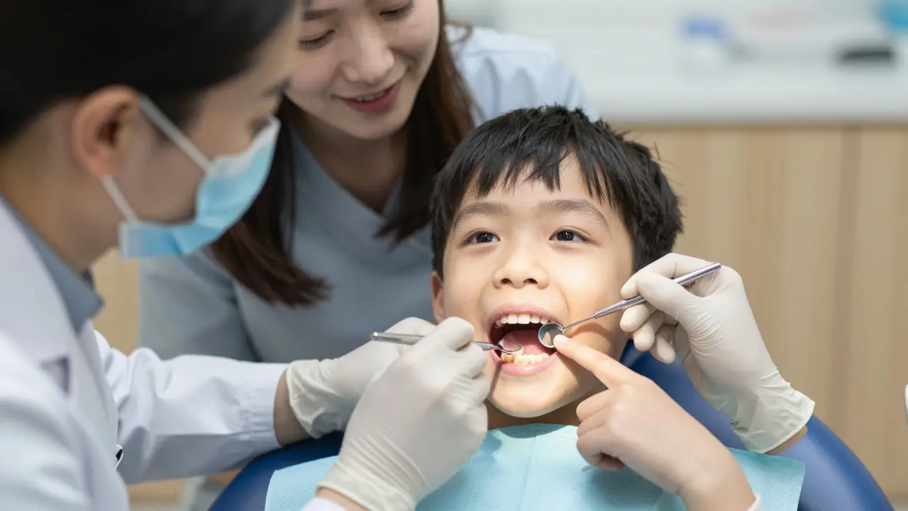 Dětský zubař vyšetřuje dítě, které má nově vyrůstlý trvalý molár za mléčným zubem.